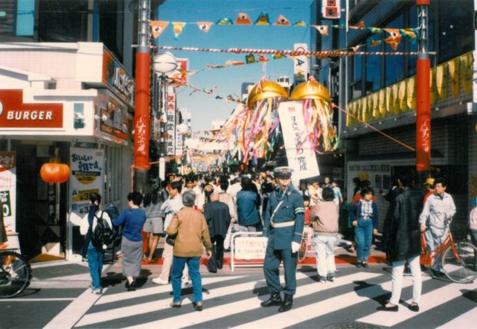 写真：すきっぷ通り完成祝のくす玉と、大勢の人でにぎわっている様子