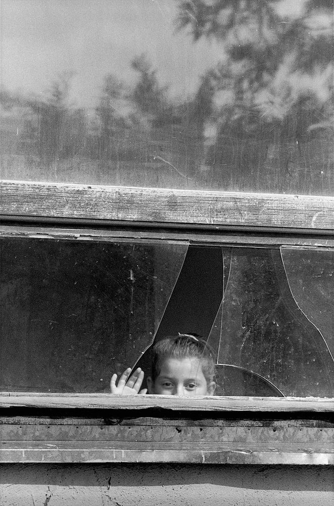 写真:壊れた窓からのぞく少女